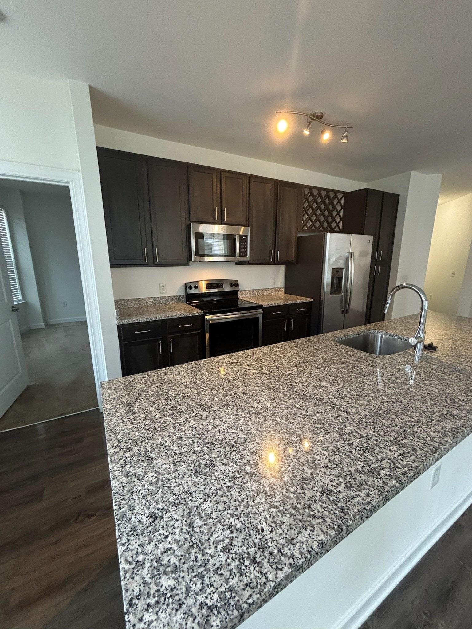 Kitchen with dark cabinets and a speckled granite island, counters cleared