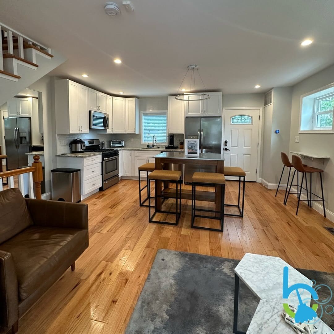 Open kitchen and living area with bar stools and clean hardwood floors
