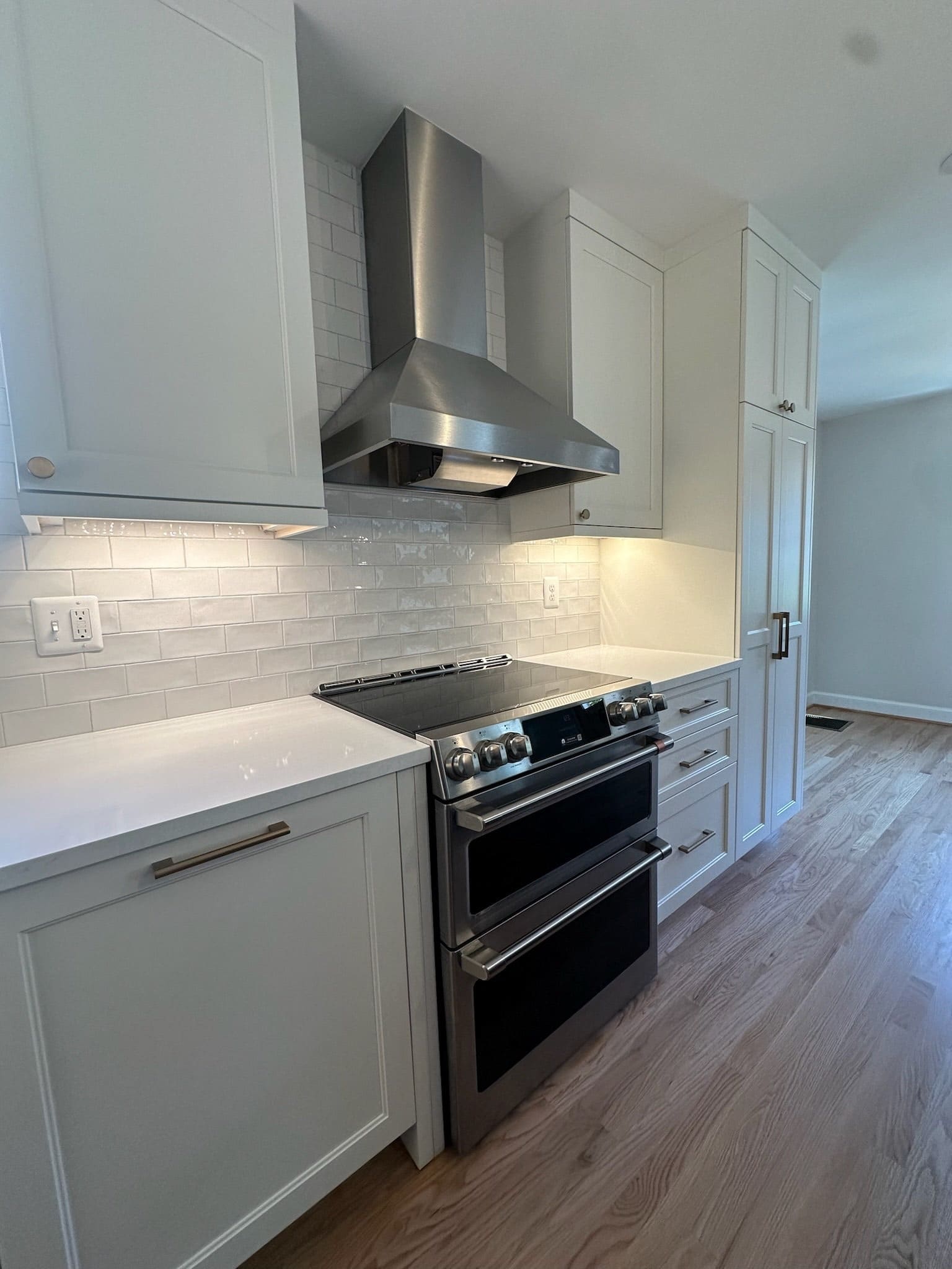 Kitchen corner with white cabinets, a stainless range and a range hood