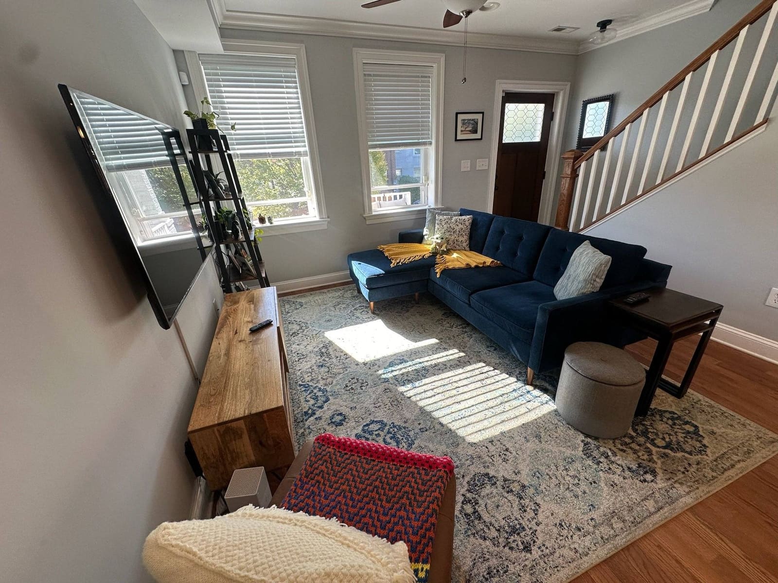 Living room with a navy sectional, patterned rug and wall-mounted TV