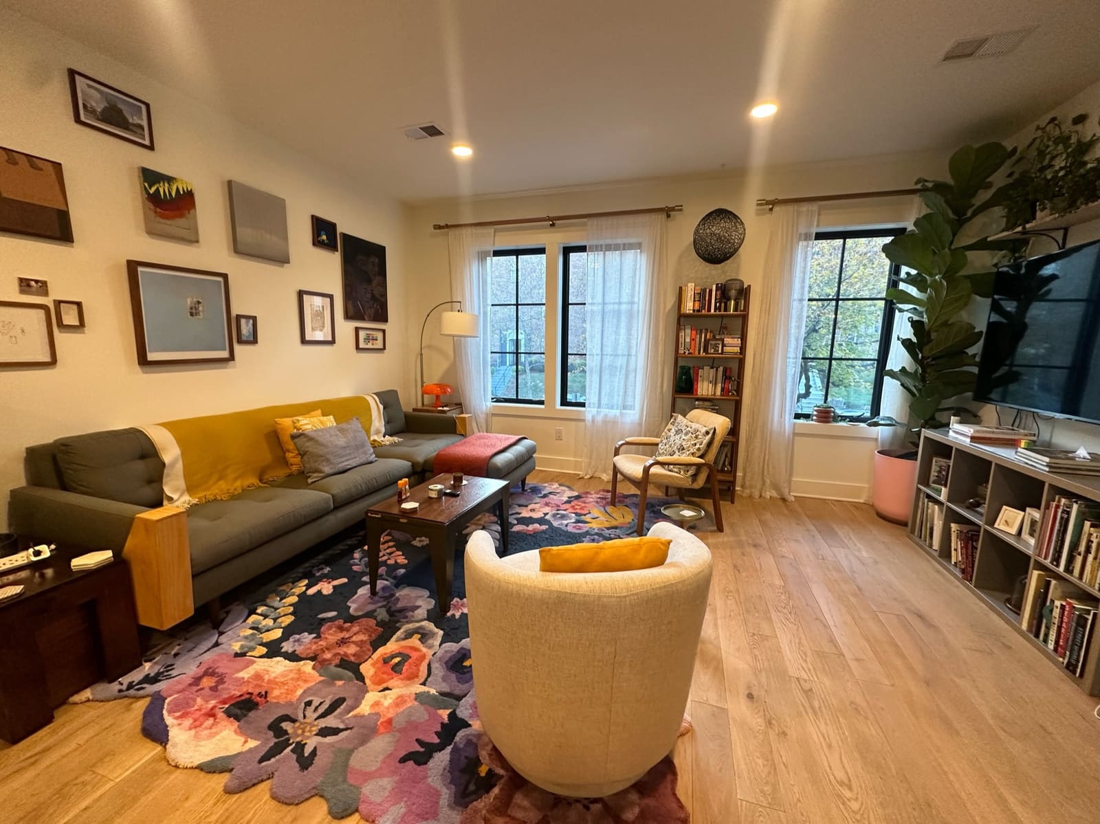 Living room with a yellow sofa, colorful rug and a gallery wall